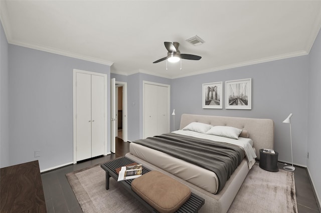 bedroom featuring visible vents, two closets, wood finished floors, and crown molding