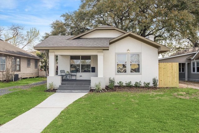 bungalow-style home with covered porch, stucco siding, and a front lawn