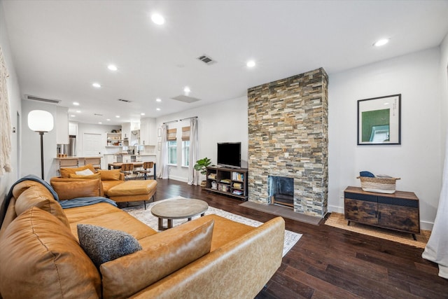 living area with dark wood finished floors, a stone fireplace, recessed lighting, and visible vents