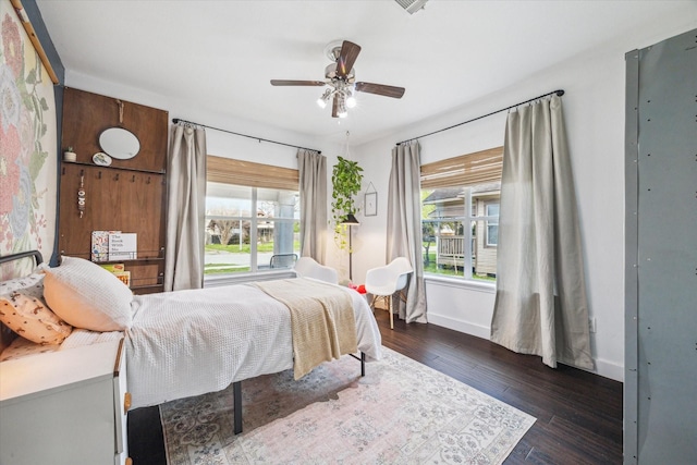 bedroom featuring ceiling fan, baseboards, multiple windows, and dark wood-style floors