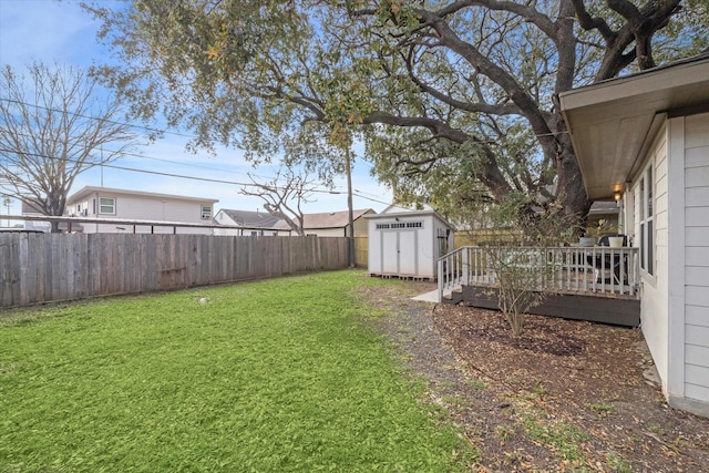 view of yard featuring a storage shed, an outbuilding, a deck, and a fenced backyard