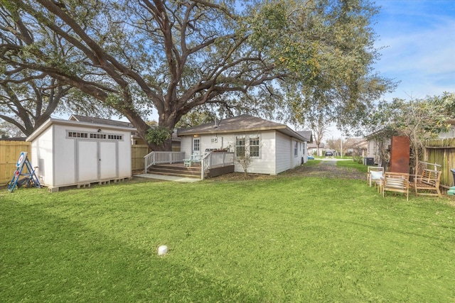 view of yard featuring an outbuilding, a wooden deck, a storage unit, and fence