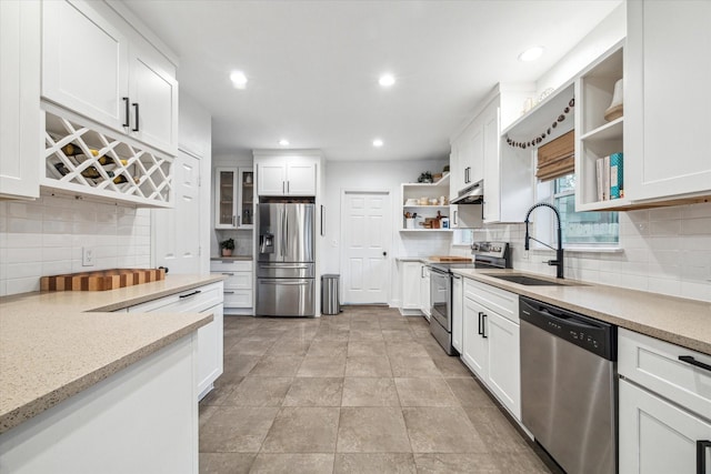 kitchen featuring open shelves, light stone counters, appliances with stainless steel finishes, white cabinetry, and a sink