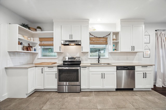 kitchen featuring open shelves, a sink, under cabinet range hood, appliances with stainless steel finishes, and light countertops