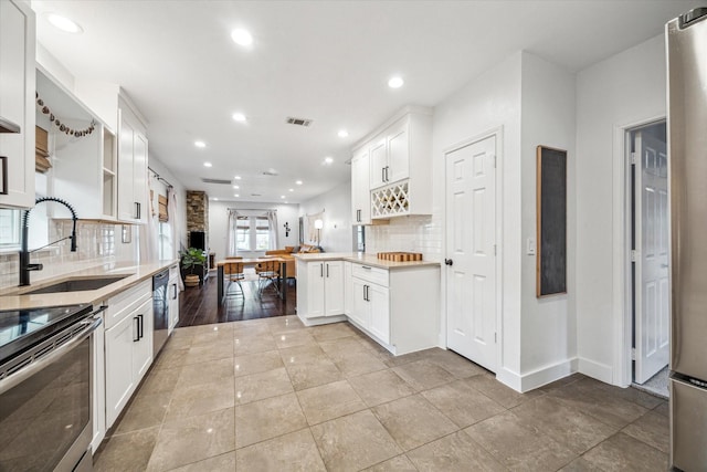 kitchen with open shelves, dishwasher, light countertops, white cabinetry, and a sink