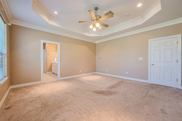 empty room featuring a raised ceiling, crown molding, visible vents, and light carpet