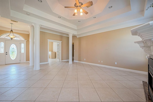 interior space featuring ceiling fan, baseboards, light tile patterned floors, a raised ceiling, and ornate columns