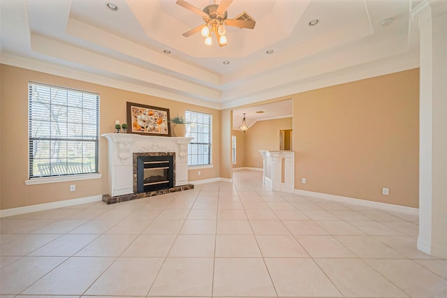 unfurnished living room featuring a tray ceiling, a healthy amount of sunlight, and a fireplace