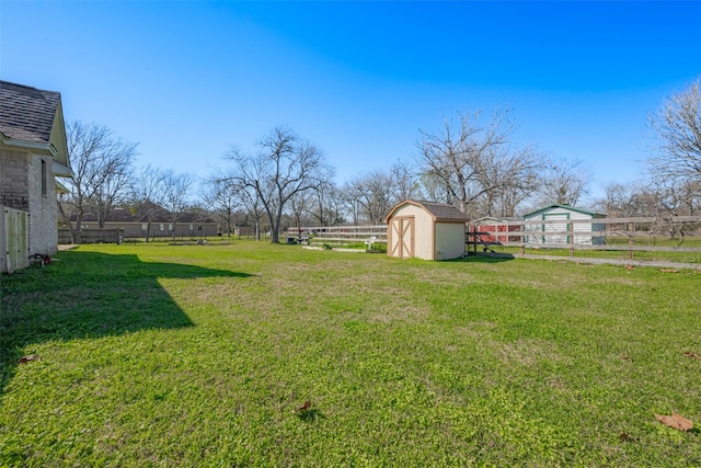 view of yard with a storage shed, fence, and an outbuilding