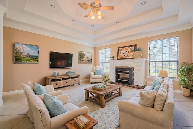 living area featuring a tray ceiling, a healthy amount of sunlight, and a premium fireplace