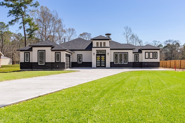 prairie-style home with stucco siding, fence, concrete driveway, an attached garage, and a front yard