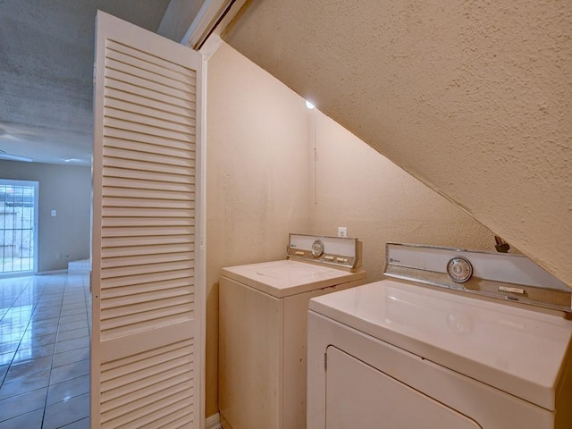 laundry area featuring washer and dryer, a textured ceiling, light tile patterned floors, laundry area, and a textured wall