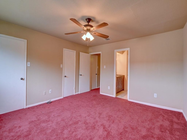 unfurnished bedroom featuring visible vents, baseboards, carpet floors, ensuite bathroom, and a ceiling fan
