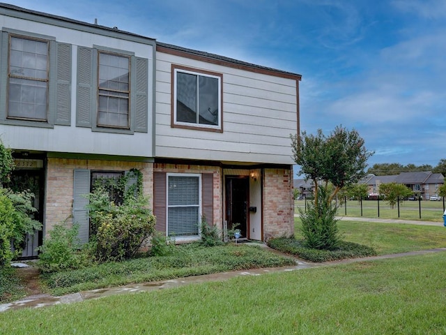 multi unit property featuring brick siding and a front lawn