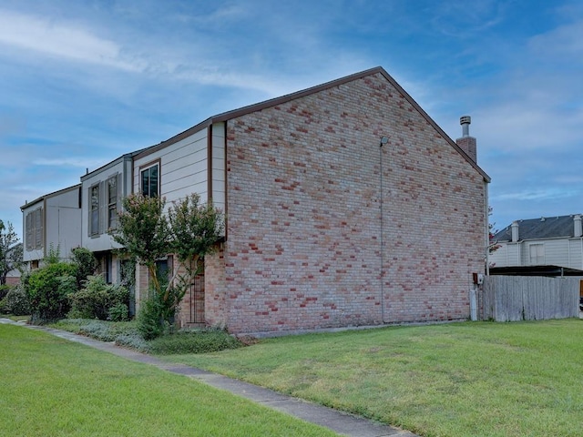view of home's exterior with brick siding and a yard