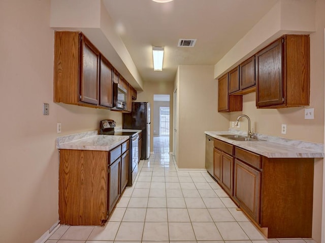 kitchen with visible vents, light countertops, light tile patterned flooring, stainless steel appliances, and a sink