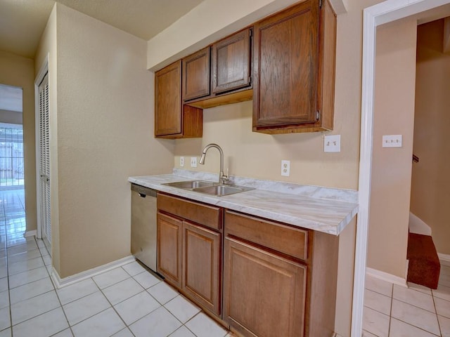 kitchen featuring dishwasher, light countertops, light tile patterned floors, brown cabinets, and a sink