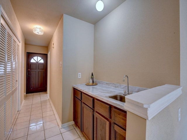 bar featuring a sink, baseboards, and light tile patterned flooring