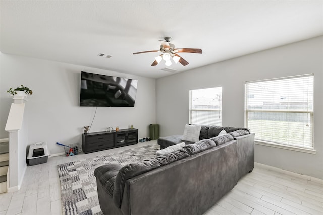 living area featuring plenty of natural light, light wood-style floors, visible vents, and ceiling fan