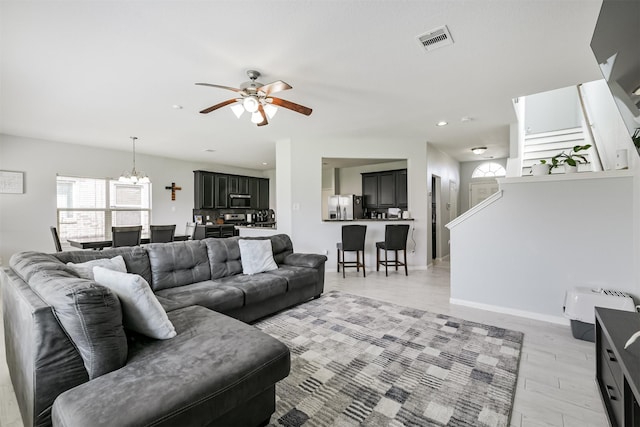 living room with visible vents, baseboards, stairs, recessed lighting, and ceiling fan with notable chandelier