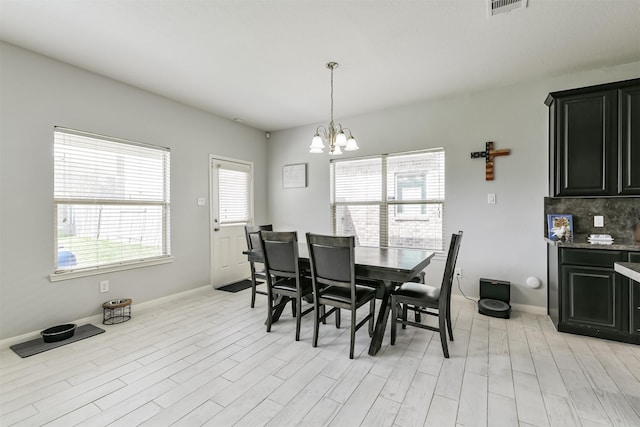 dining area featuring visible vents, baseboards, light wood-style floors, and an inviting chandelier