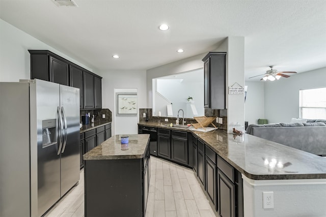 kitchen with a kitchen island, a sink, black dishwasher, stainless steel refrigerator with ice dispenser, and open floor plan