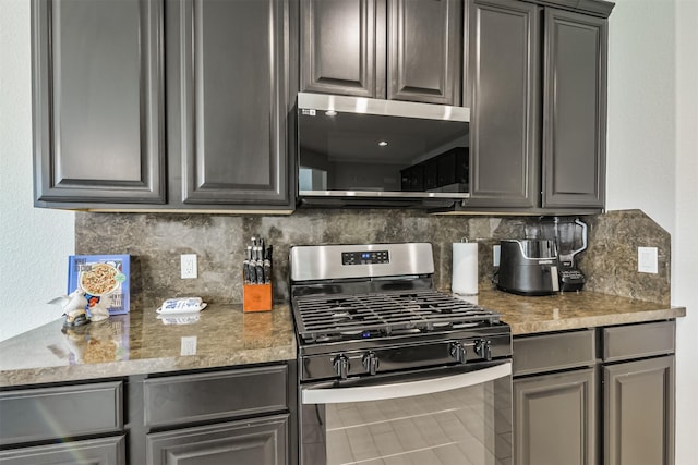 kitchen with light stone counters, backsplash, appliances with stainless steel finishes, and gray cabinetry