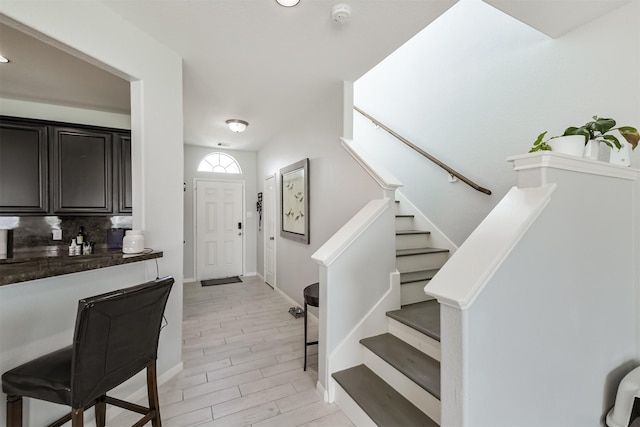 foyer entrance featuring wood finish floors, stairway, and baseboards