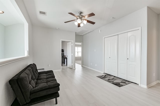 living area featuring baseboards, visible vents, attic access, ceiling fan, and light wood-type flooring