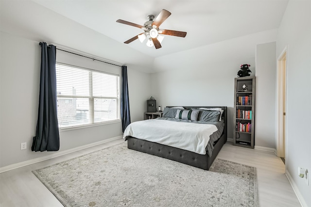 bedroom featuring ceiling fan, light wood-style floors, and baseboards