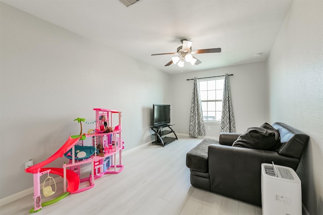 living area with visible vents, ceiling fan, baseboards, and wood finished floors