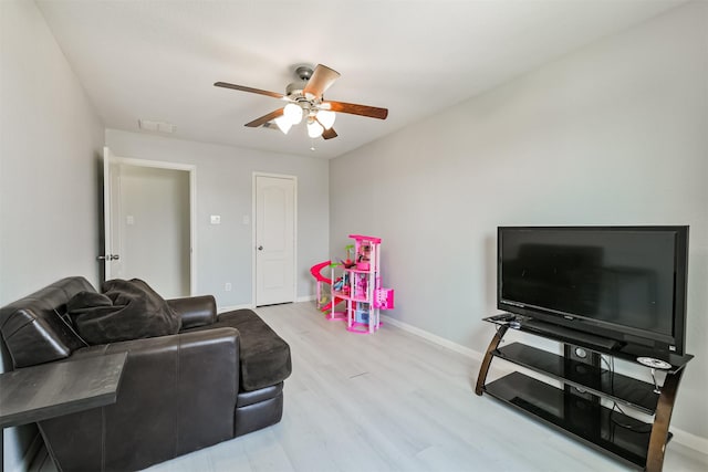 living area with ceiling fan, visible vents, baseboards, and wood finished floors