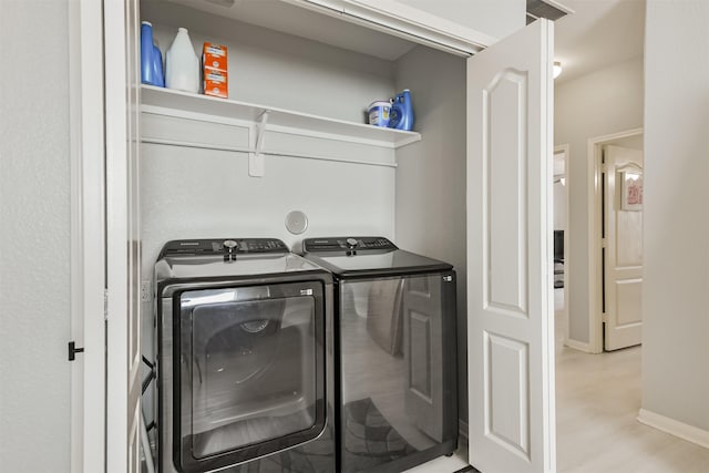 washroom featuring laundry area, washer and dryer, baseboards, and light wood-style floors