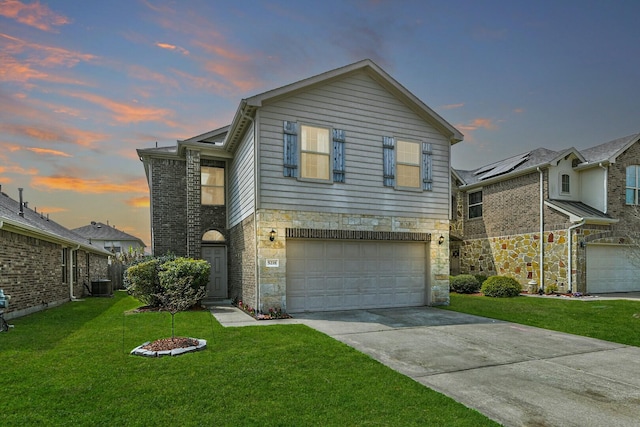 traditional-style house with a lawn, stone siding, cooling unit, concrete driveway, and an attached garage