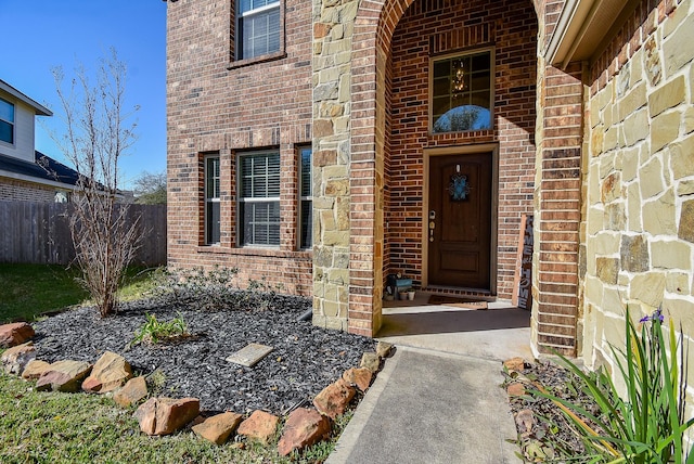 doorway to property with brick siding and fence