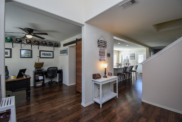 corridor with a barn door, baseboards, visible vents, and wood finished floors