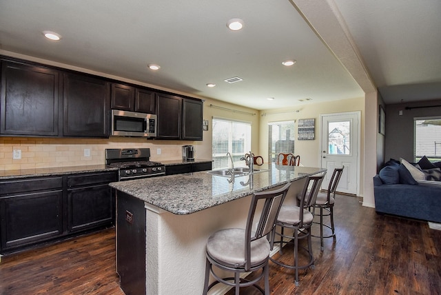 kitchen featuring stone counters, dark wood-type flooring, appliances with stainless steel finishes, and a sink