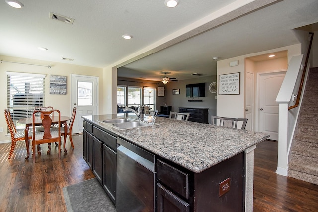 kitchen featuring visible vents, a center island with sink, a sink, dark wood-style floors, and dishwasher