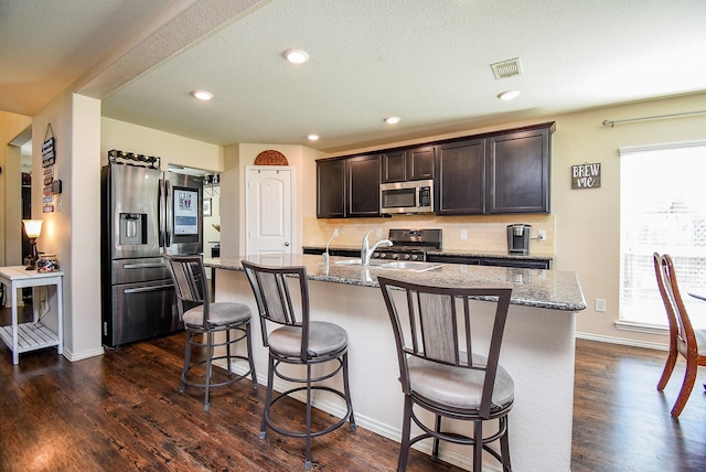 kitchen with a sink, stainless steel appliances, visible vents, and dark wood finished floors