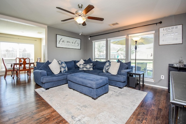 living room featuring plenty of natural light, dark wood-style floors, visible vents, and baseboards