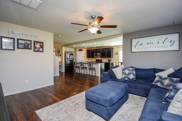 living room with visible vents, baseboards, wood finished floors, and a ceiling fan