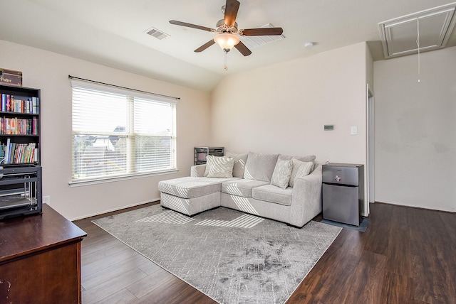 living area featuring attic access, visible vents, dark wood-style flooring, and vaulted ceiling