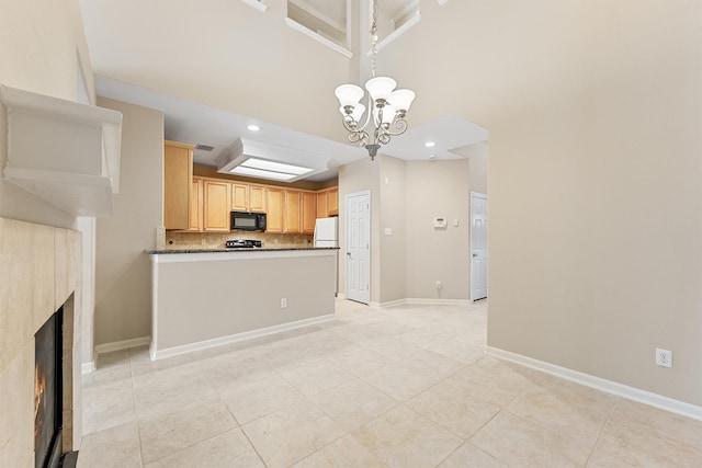 kitchen featuring freestanding refrigerator, a tile fireplace, black microwave, dark countertops, and backsplash