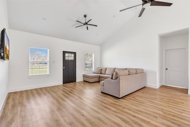 living area with baseboards, light wood-style floors, ceiling fan, and high vaulted ceiling