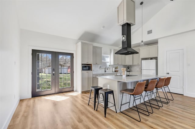 kitchen featuring visible vents, built in microwave, french doors, freestanding refrigerator, and island range hood