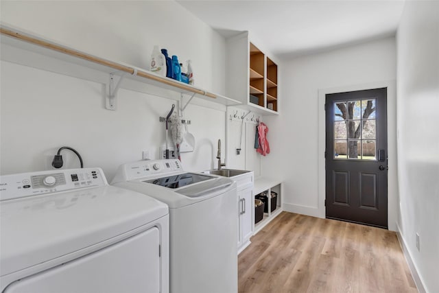 laundry area with washer and dryer, a sink, cabinet space, light wood finished floors, and baseboards