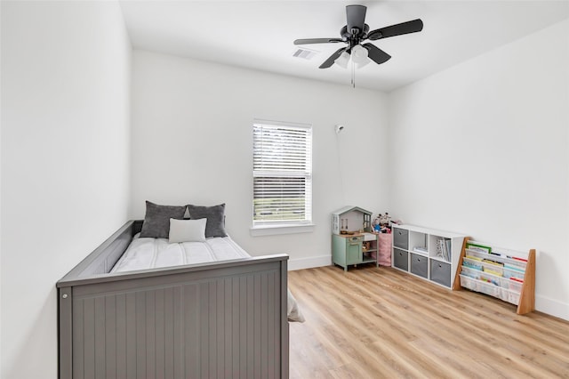 bedroom featuring light wood finished floors, visible vents, baseboards, and ceiling fan