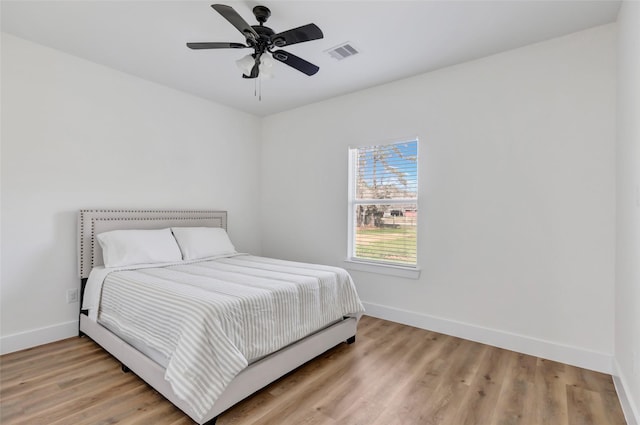 bedroom with visible vents, baseboards, a ceiling fan, and light wood finished floors