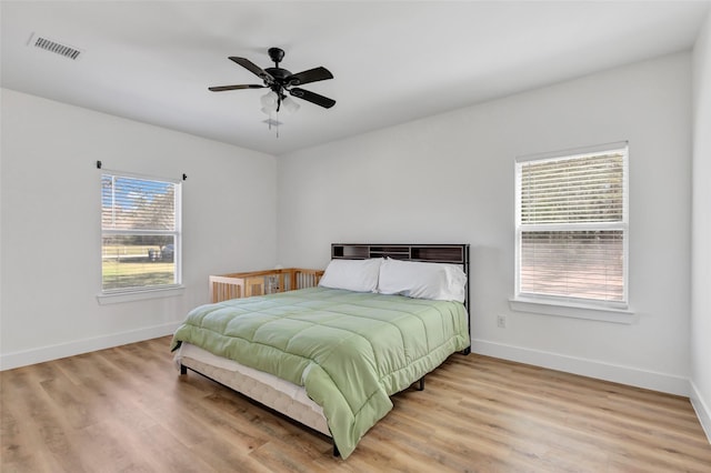 bedroom featuring a ceiling fan, visible vents, baseboards, and light wood finished floors