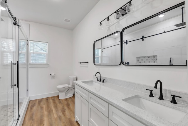 bathroom with a sink, wood finished floors, toilet, and a stall shower